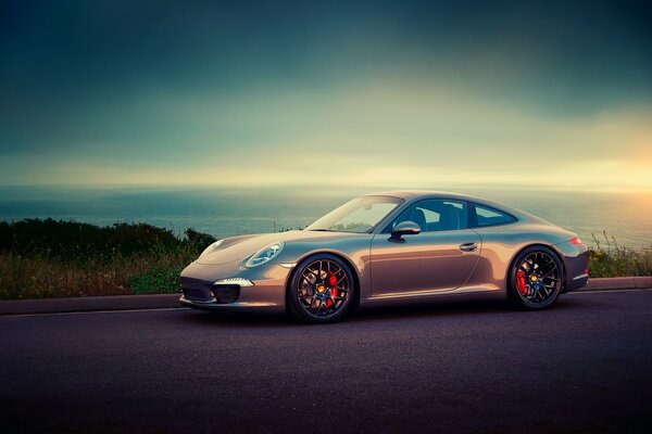 Voiture de sport Porsche lilas sur la route sur fond de mer