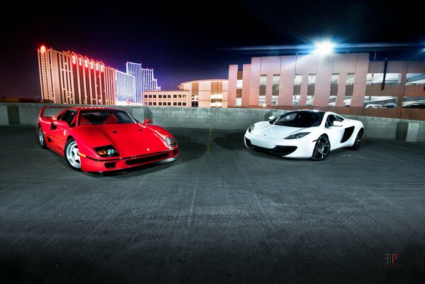 Red and white Ferrari cars in the parking lot in the night city