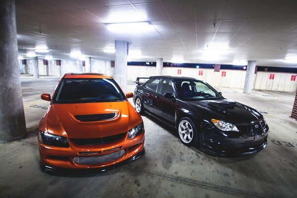 Orange mitshub and black subaru in the parking lot