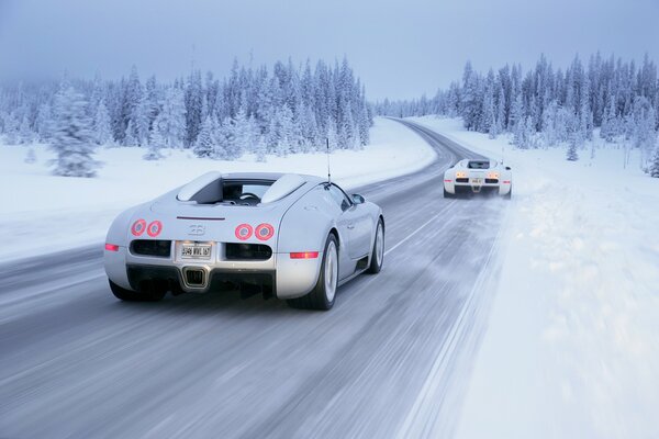 Белый Bugatti veyron на переднем приводе выполняет движение по зимней дороге