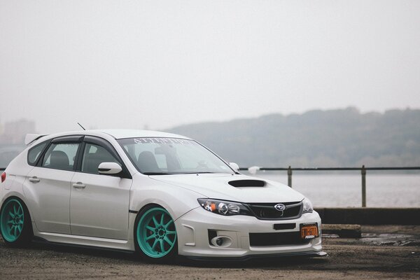 White subaru impreza with turquoise wheels