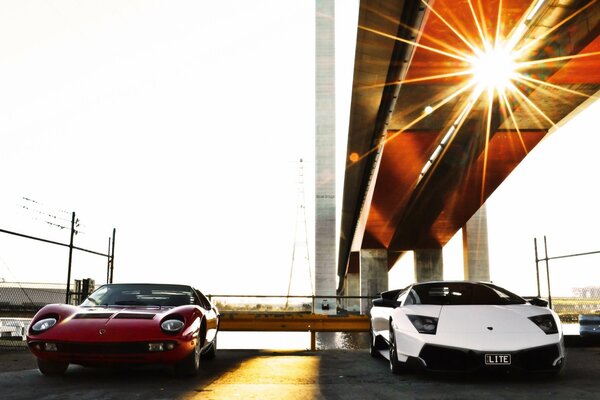 Two sports cars stand side by side in the rays of the bright sun