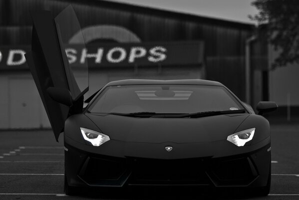 A black Lamborghini with an open door lights up