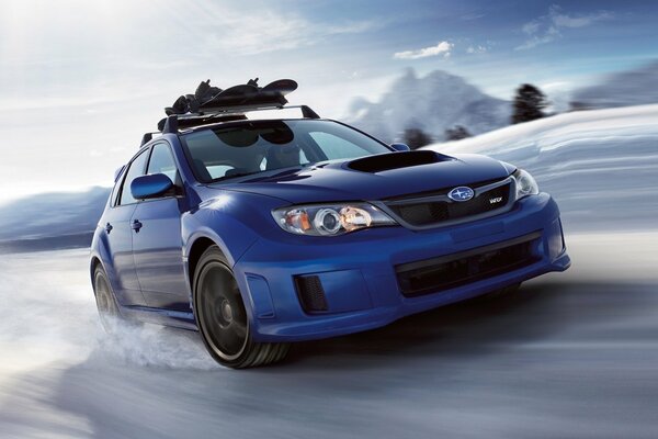 Blue subaru impreza at speed on a snowy highway