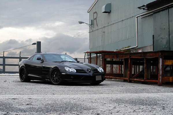 Black Mercedes on the background of a building and a cloudy sky