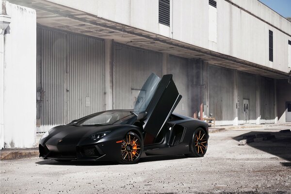 Lamborghini negro con la puerta abierta en el fondo de un almacén abandonado