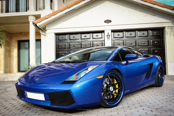 El coche azul de Lamborghini está parado cerca de la casa