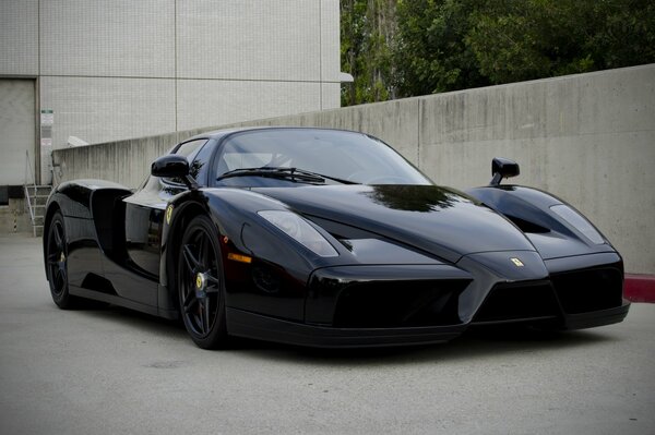 A black Ferrari stands in front of a concrete building