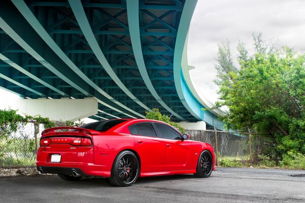 L auto sportiva rossa si trova sotto un ponte moderno in cemento, vista posteriore