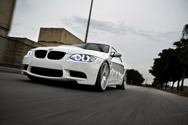 A white bmw is driving on a city road