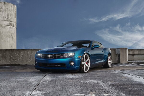 Chevrolet camaro blau auf einem Parkplatz unter den Wolken