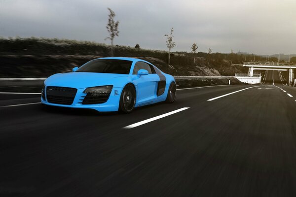 A bright blue matte sports car rushes along the evening highway