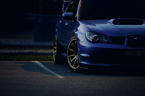 Blue Subaru in the parking lot in the evening