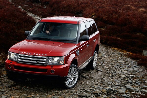 Red range rover on a rocky road