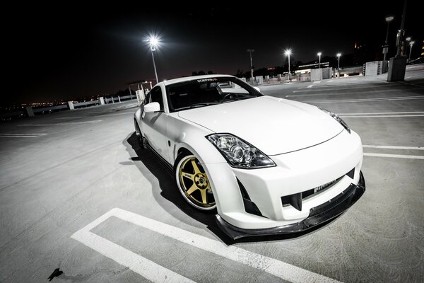 A tuned Nissan stands in the parking lot at night