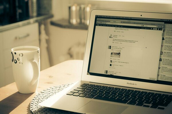 Tazza di caffè con il computer portatile in cucina