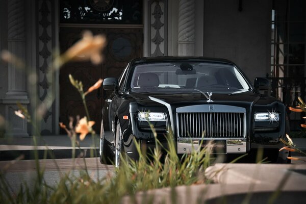 Black Rolls Royce car on the background of a house