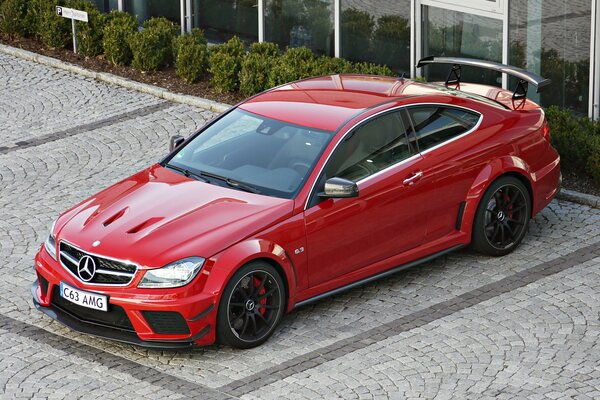 Red Mercedes C63 next to a luxury building