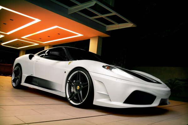 A white Ferrari car driving out from under the canopy