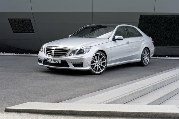 A gray glossy Mercedes Benz is parked near the building