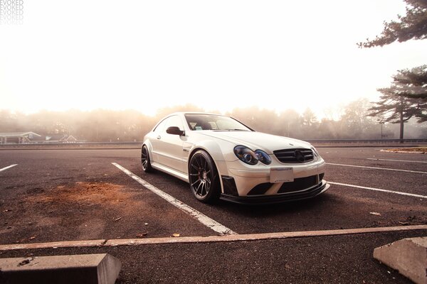 Mercedes in the parking lot against the background of a forest in a thick fog