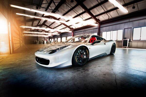 A white sports car is in the hangar