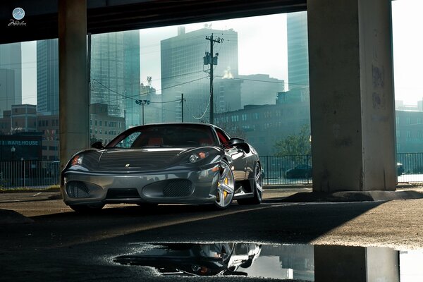 Silver metal Ferrari car in an abandoned building against the backdrop of high-rise buildings