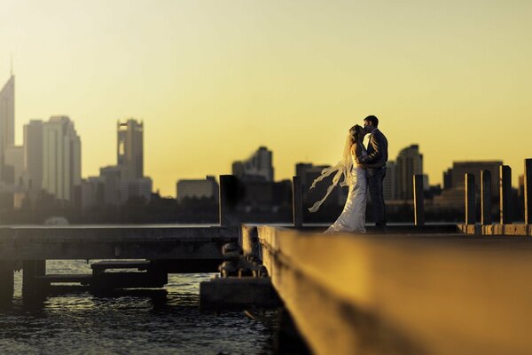 Recién casados besándose en el muelle durante el atardecer