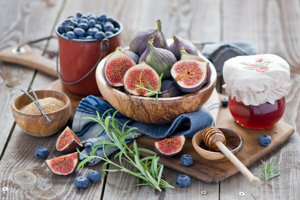 Feigen in einer Schüssel, ein Löffel Honig und Blaubeeren