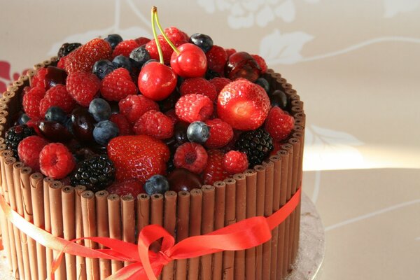 Ein Kuchen mit frischen Beeren, der mit einem roten Band gebunden ist