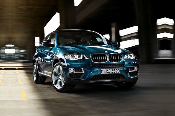 La BMW X6 blu guida nella metropoli notturna