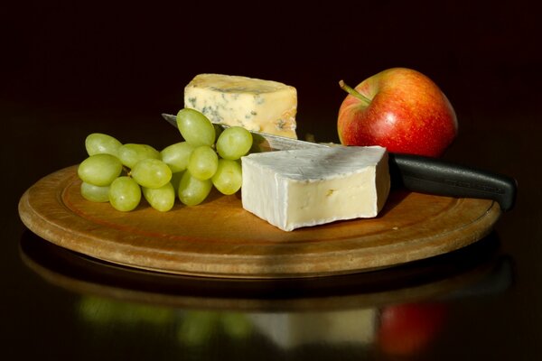 Sur la table, deux types de fromage et de fruits