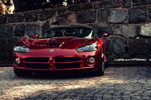 Burgundy sports car on the background of a stone wall