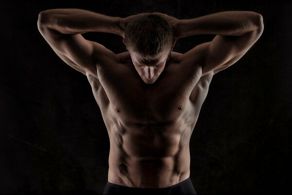 Beautiful torso of a man with falling shadows on the press