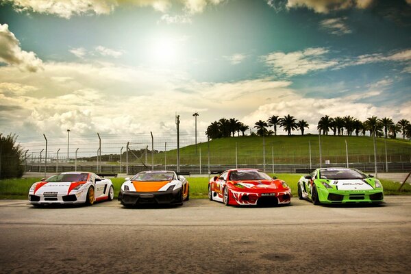 Three Lamborghini cars and one Ferrari car with racing color schemes