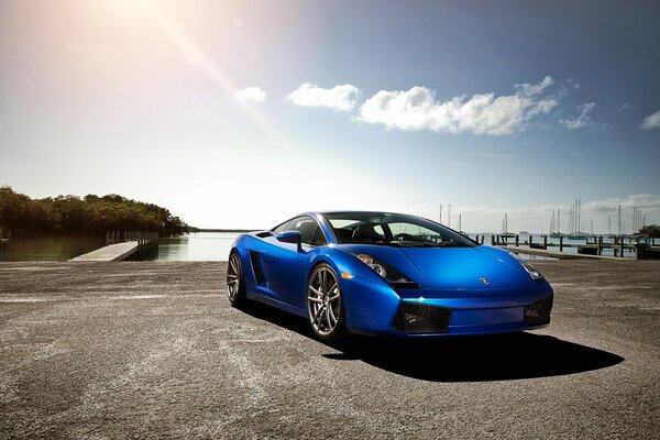 Blue Lamborghini on the background of water, marina and sky