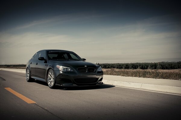 Black new bmw rides on the road in front