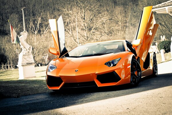 Orange lamborghini car with open doors on the road