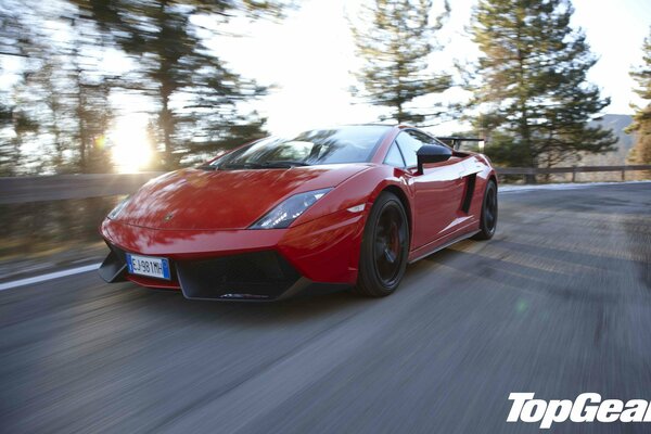 A red supercar rides on a mountain serpentine