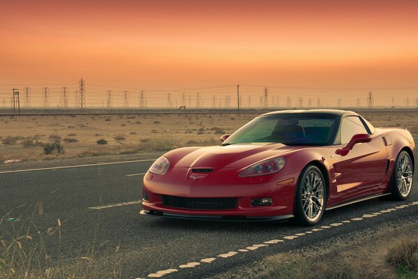 Red corvette rides at sunset on the road