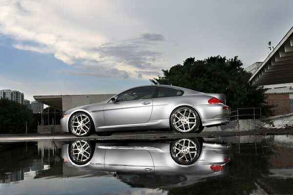 Un BMW plateado con reflejo en un charco