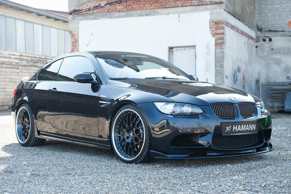 Black BMW M3 Hamann stands against a wall with broken masonry