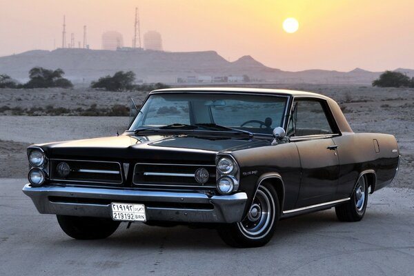 Retro car Pontiac 1963 on a deserted road under the sun