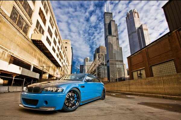 Blue BMW in the alley of the metropolis against the backdrop of skyscrapers