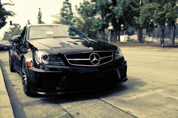 A black Mercedes C63 is parked on the street