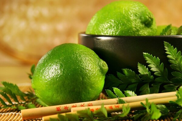 Limes dans une tasse à côté de baguettes chinoises