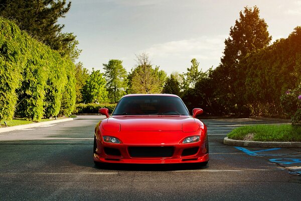 A red Mazda stands on the road in the garden