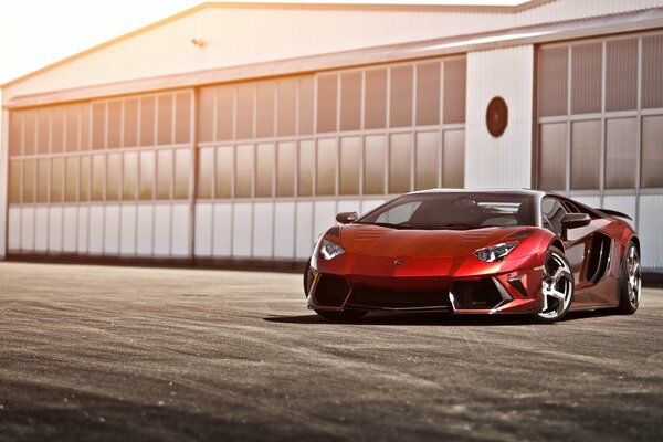 On the background of the hangar is a red Lamborghini 