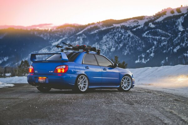 Blauer Subaru auf dem Hintergrund der winterlichen Berglandschaft