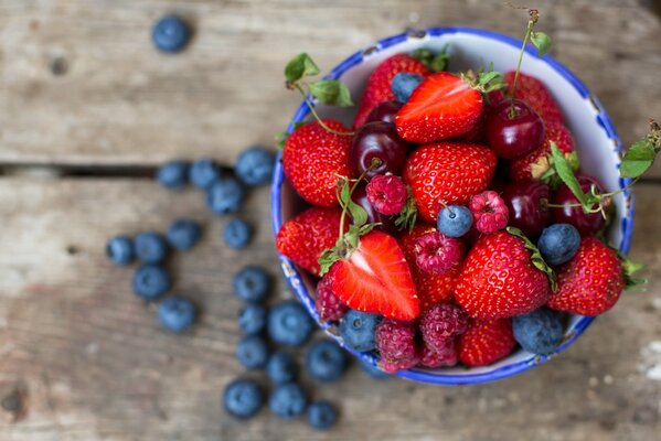 Fragole, lamponi, mirtilli in una tazza profonda